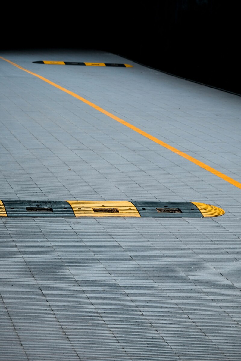pexels photo 1187313 1187313 Yellow and black speed bumps on a gray urban pavement with clear lines marking the parking area.