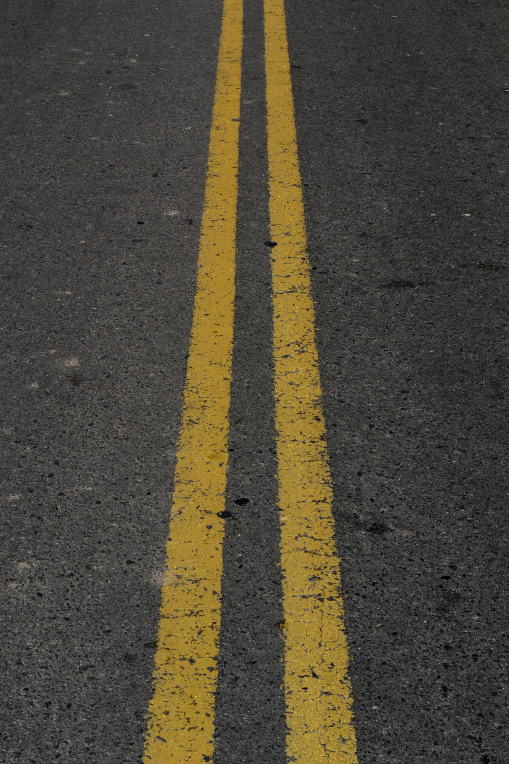pexels photo 16682389 16682389 Detailed view of double yellow lines on asphalt road surface.