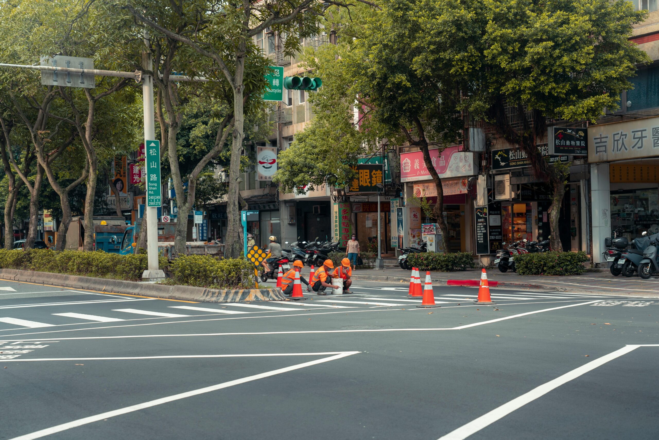pexels photo 18110523 18110523 Workers painting road lanes in a bustling city intersection.