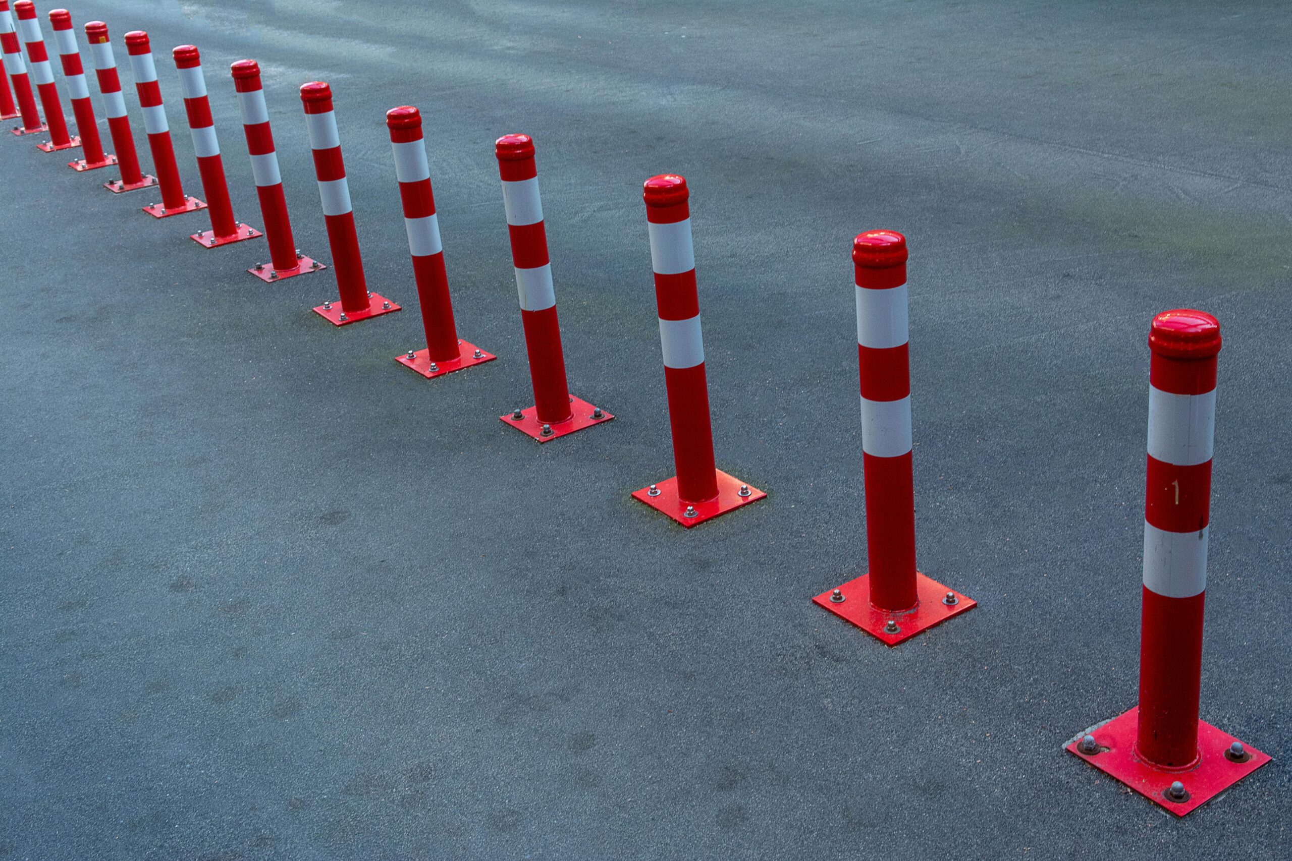 pexels photo 24827190 24827190 Line of red and white bollards on asphalt road for traffic control and safety.