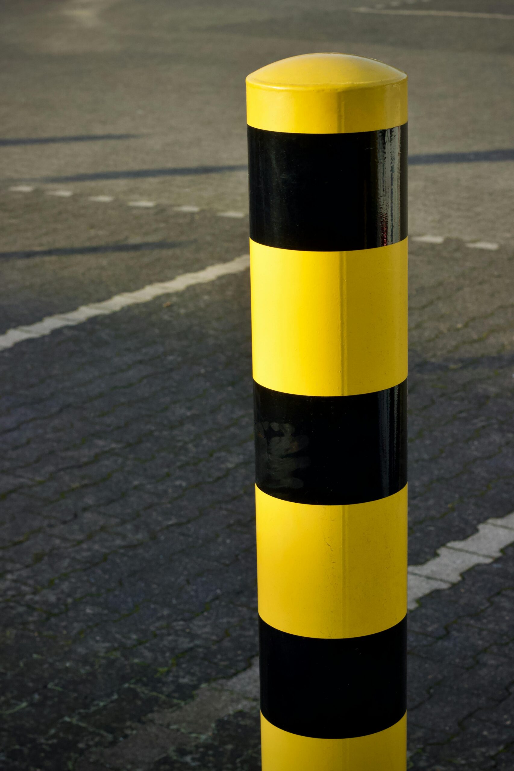 pexels photo 36591257 36591257 A yellow and black striped traffic bollard stands on a paved road surface.